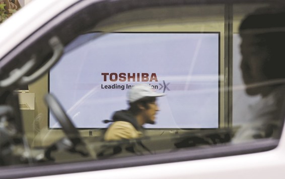 A Toshiba Corp logo displayed on one of its television sets is seen through a vehicle in Tokyo. The Japanese firm raised its forecast for first-half operating profit to u00a570bn ($696mn) from u00a530bn.