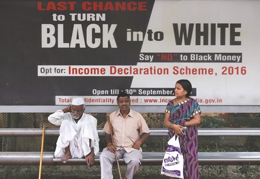 Passengers wait in front of an income tax billboard at a bus stop in New Delhi. Many entrepreneurs arenu2019t so keen on a scheme that offers little relief: they would have to pay 45% in back tax and penalties, and even then would not be sure of keeping the taxman off their back.