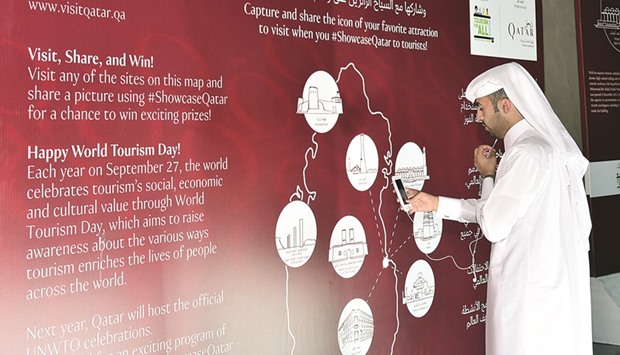A Qatari participant enjoying the picture-taking session at one of the life-size photo frames. Right: A visitor takes a picture of the eight landmarks in Qatar where the photo life-size frames are located. PICTURE: QTA