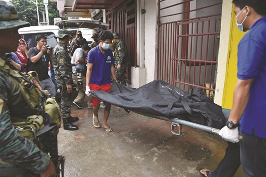 Police special action force personnel look on as funeral parlour workers carry the body of drug convict Peter Co, who was killed in a knifing incident inside the national penitentiary in suburban Manilau2019s Muntinlupa City  yesterday.