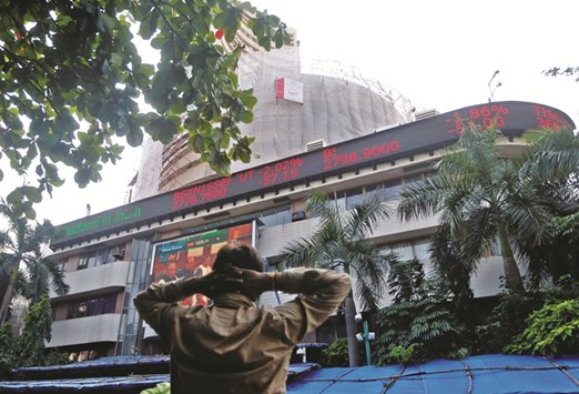 A man watches a large screen displaying Indiau2019s benchmark share index on the facade of the Bombay Stock Exchange building. The Sensex slumped 1.6% to a one-month low yesterday.