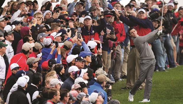 The crowd watches as Rory McIlroy of Northern Ireland (R) swings from the rough during a practice round ahead of 41st Ryder Cup at Hazeltine National Golf Course in Chaska, Minnesota.
