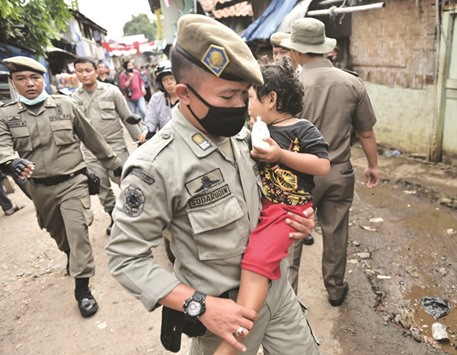 This picture taken on Wednesday shows a civil police officer carrying a girl to a safe place during the demolition of over 300 settlements of the Bukit Duri neighbourhood, located on the Ciliwung river banks, in order to improve the riverside infrastructure planned by the government in Jakarta.