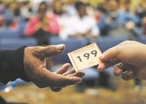 A tax officer hands a number to a man queueing for tax amnesty at the countryu2019s tax headquarters in Jakarta.