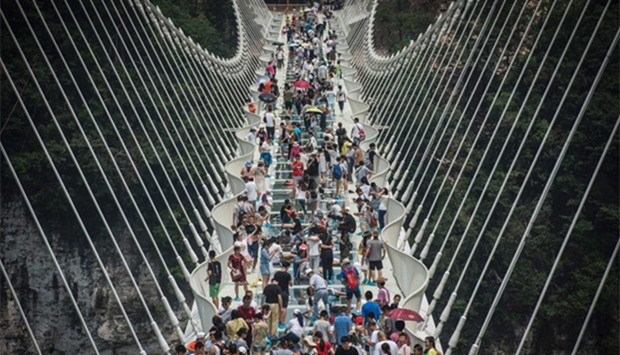 visitors crossing the world's highest and longest glass-bottomed bridge