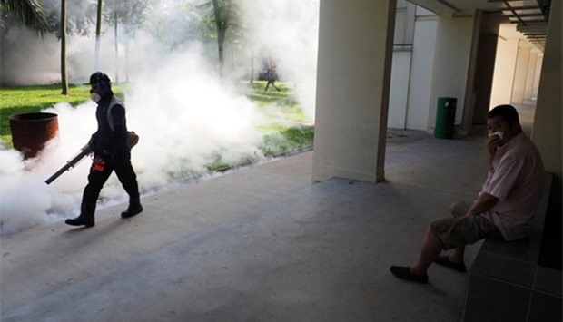A resident shields his nose as a pest control officer carries out fogging in the Aljunied Crescent cluster in Singapore.