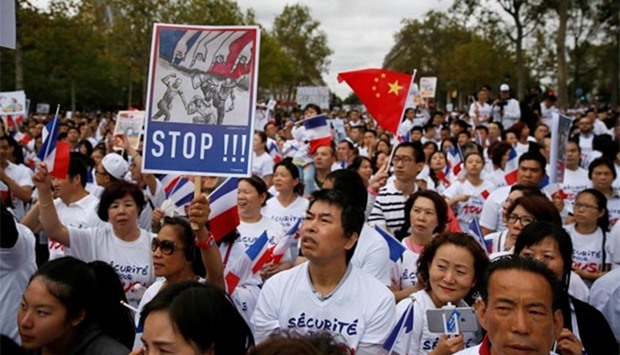 Demonstrators hold signs at a rally of the Chinese community to raise awareness about recent racists attacks in Paris, on Sunday.