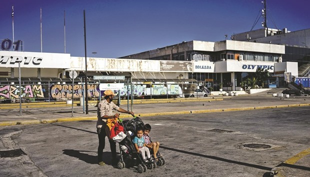 A migrant is seen with his children outside the former international airport in Athens, currently used as a temporary camp for migrants and refugees.