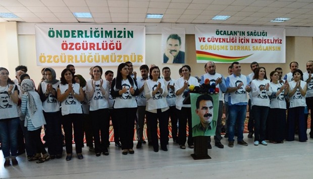 Turkey's pro-Kurdish People's Democratic Party (HDP) co-chair Sebahat Tuncel (C) applauds after speaking on September 5, 2016 in Diyarbakir as she stands amongst group of people wearing T-shirts featuring jailed PKK leader Abdullah Ocalan, before starting a hunger strike to demand news about the Kurish leader.