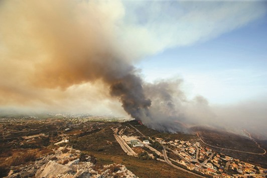 Smoke from forest fires rises into the air along the coastline near the Spanish resort of Javea, Valencia region, yesterday.