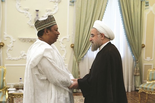 A handout picture provided by the office of Iranian President Hassan Rouhani yesterday shows him shaking hands with the Opec secretary general, Nigeriau2019s Mohammed Barkindo (left), during a meeting in Tehran. Iran has been the main factor preventing an output deal between Opec and non-Opec Russia as Tehran argued it should be excluded from any such agreement before its production recovers from Western sanctions that ended in January.