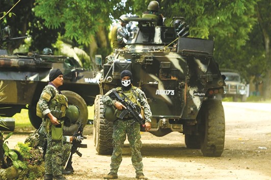 Soldiers standing guard next to an Armoured Personnel Carrier (APC), inside a military camp in Jolo, Sulu province, in the southern island of Mindanao, as they prepare for an operation against the Abu Sayyaf group.