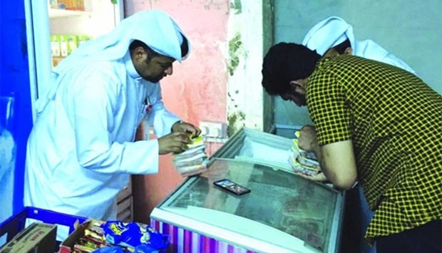 Doha Municipality inspectors examine products at a store.