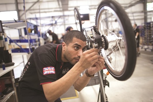 An employee adjusts an internal hub gear on a folding bicycle in the assembly area inside the Brompton Bicycle factory in London. The UKu2019s factory output fell 0.9% from June, far exceeding the 0.3% decline forecast in a Bloomberg survey, Office for National Statistics data published yesterday show.