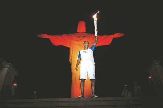 Brazilian judoka Rafaela Silva, who won the gold medal during the Rio 2016 Olympic Games, holds up the torch for the Rio 2016 Paralympic Games in front of the statue of Christ the Redeemer atop Mount Corcovado in Rio de Janeiro. (AFP)