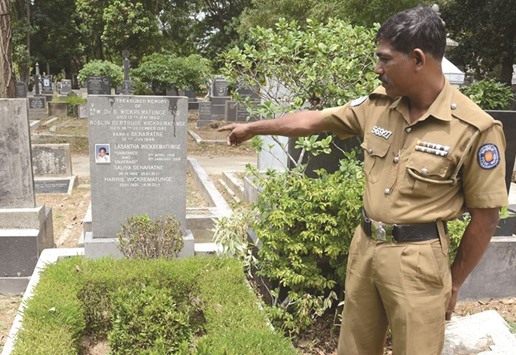 A Sri Lankan policeman points towards the gravestome of anti-establishment editor Lasantha Wickrematunga at the general cemetery in Colombo yesterday.