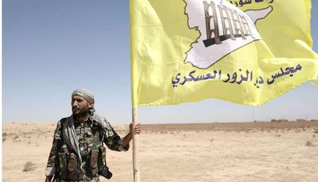 A fighter from Deir al-Zor military council which fights under the Syrian Democratic Forces (SDF) holds the council's flag in the village of Abu Fas, Hasaka province, Syria
