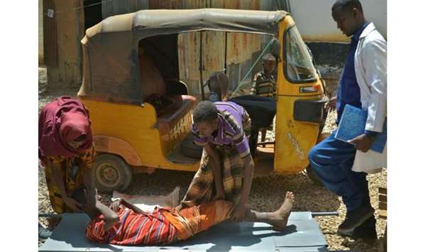 A boy with cholera is helped onto a stretcher.  Picture courtesy: Concise