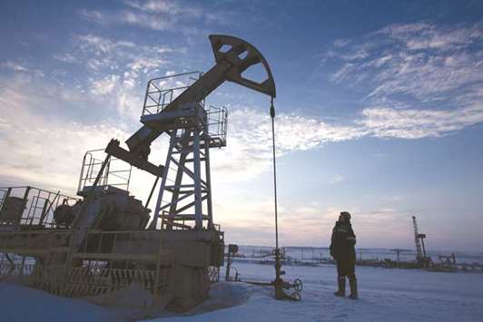 A worker inspects a pumping jack during oil drilling operations in an oilfield operated by Bashneft in Russia. Countries like Russia should lock in future oil revenues using financial instruments, according to Goldman Sachs.