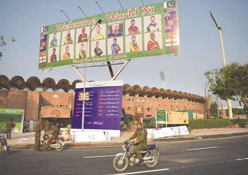 Pakistani policeman rides past a billboard featuring International World XI cricketers outside the Gaddafi cricket stadium in Lahore yesterday. (AFP)