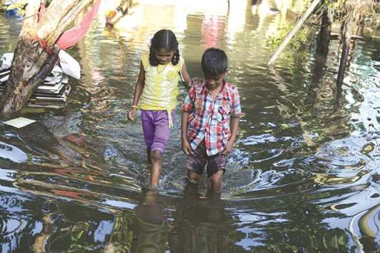 Two children wade through a flooded street after rains lashed Bengaluru yesterday.