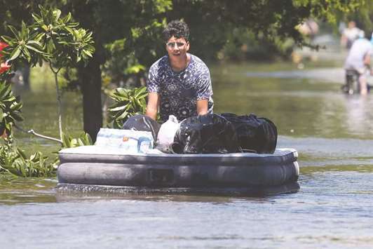 A woman uses an air mattress to float possessions out of a flooded area of Port Arthur, Texas, yesterday.