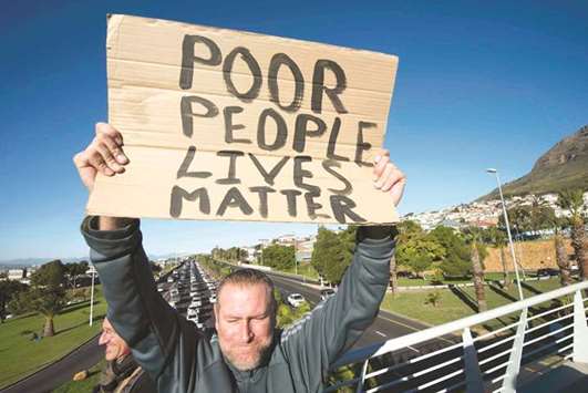 A July 11, 2017, file photo of activist Shane van der Mescht holds a sign during a protest calling for affordable housing close to the city centre for disadvantaged people, organised by the group Reclaim the City, over the N2 highway in Woodstock, Cape Town.