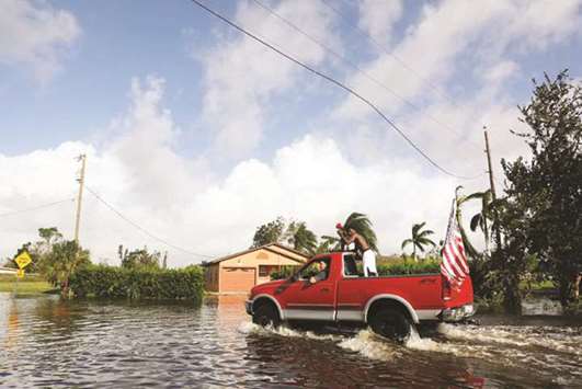 Jizreel Plancher calls out from the back of a truck to see if people need help the morning after Hurricane Irma swept through the area in Naples, Florida.