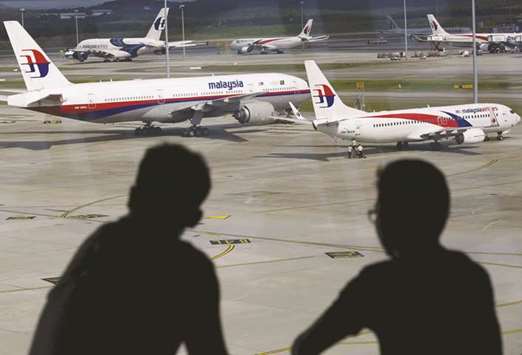 Men watch Malaysia Airlines aircraft at Kuala Lumpur International Airport. The airline will announce a deal to buy eight widebody Boeing 787 jets during the visit of Prime Minister Najib Razak to the US, two industry sources said yesterday.