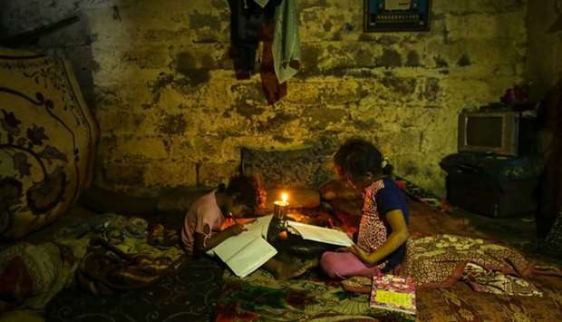 Palestinian children do their homeworks during a power cut in an impoverished area in Gaza City.