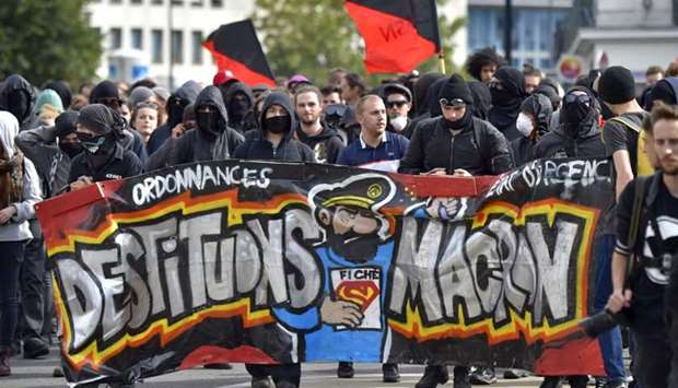 People march behind a banner reading ,Let's depose Macron, (refering to French President Emmanuel Macron) during a protest called by several French unions against the labour law reform.