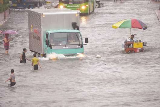 Residents and motorists manoeuvre along a flooded main street in Manila yesterday, after tropical depression locally codenamed u201cMaring,u201d hit the eastern town of Mauban before moving northwest across the main island of Luzon and passing just beside Manila, the government weather station said.