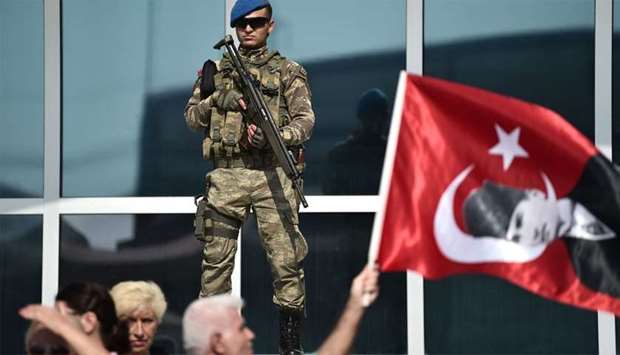A Turkish gendarme stands guard while a protester waves a flag with an image of Mustafa Kemal Ataturk, founder of modern Turkey