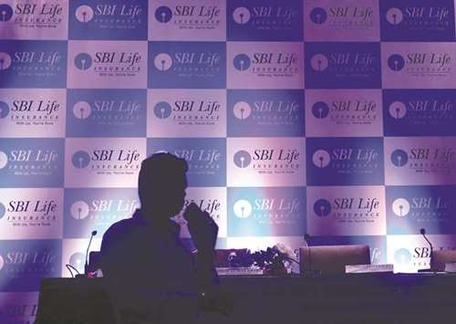 A man walks past a podium set up at the venue of a news conference to announce the launch of initial public offering by SBI Life Insurance in Mumbai yesterday.