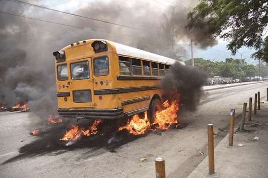 A bus with passengers aboard drives over burning tires placed by demonstrators during an anti-government protest in the centre of the Haitian capital Port-au-Prince.