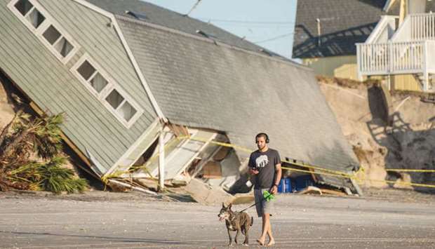 Jose Orosz walks his dog by a beachfront home destroyed by Irma.