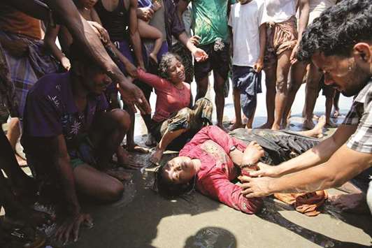 A Rohingya refugee woman cries as her relative lost consciousness after a boat capsized on the shore of Shah Porir Dwip while crossing the Bangladesh-Myanmar border, in Teknaf, Bangladesh.