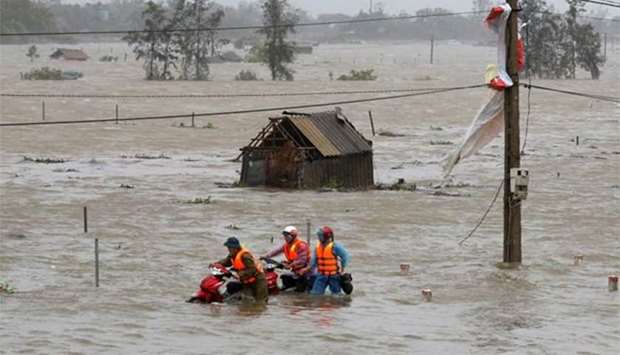 People recover motorbikes from a flooded fields while the Doksuri storm hits in Ha Tinh province, Vietnam on Friday.