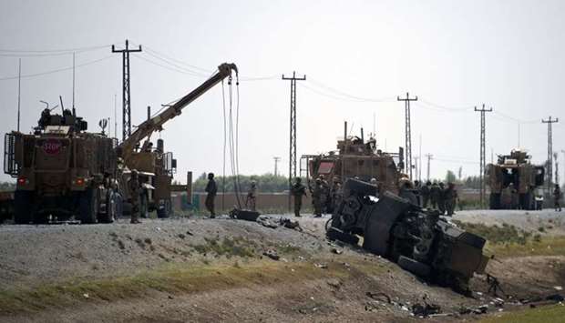 NATO soldiers keep watch near the wreckage of their vehicle at the site of a Taliban suicide attack in Kandahar