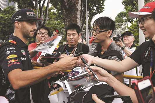 Red Bullu2019s Australian driver Daniel Ricciardo (left) signs autographs as he arrives for the first practice session for the Singapore Grand Prix yesterday. (AFP)