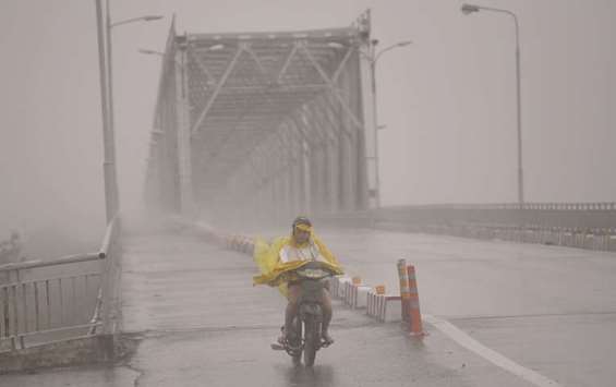 A woman rides a motorcycle across a bridge on a highway in the central province of Ha Tinh as Typhoon Doksuri makes landfall to the countryu2019s central coast yesterday.