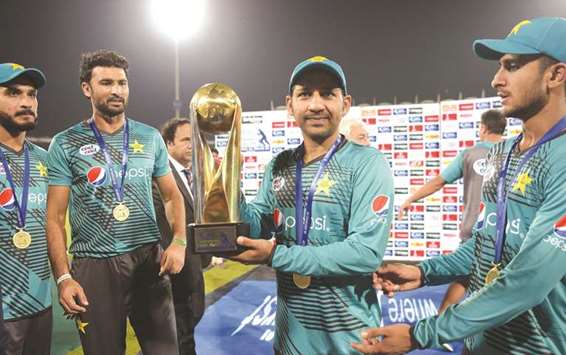 Pakistani cricket captain Sarfraz Ahmad (centre) holds the trophy after winning the third and final Twenty20 International against World XI at the Gaddafi Cricket Stadium in Lahore yesterday. (AFP)