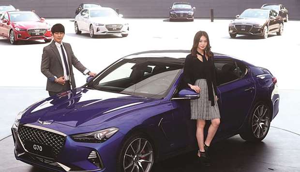 Models pose for photographs with a Genesis G70 during its unveiling ceremony in Namyangju, South Korea yesterday. Starting from $33,000, the sporty four-door offers bang for the buck as it takes on rivals including affiliate Kia Motoru2019s Stinger sedan and BMWu2019s 3 series.