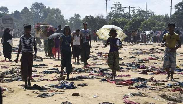 Rohingya Muslim refugees walk past discarded clothing on the ground at the Bhalukali refugee camp near Ukhia.
