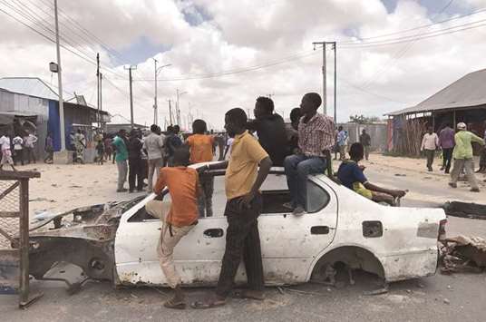 Protesters use the wreckage of a car to block the street during fighting between the military and police, backed by intelligence forces, in Mogadishu.