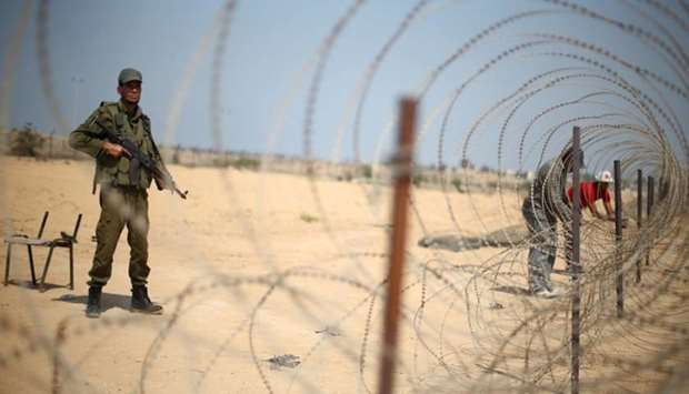 A member of the Palestinian security forces, loyal to Hamas, stands guard as men set up a barbed wire on the border with Egypt, in Rafah in the southern Gaza Strip.