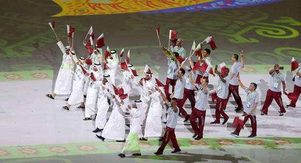 Members of the Qatar delegation wave flags as they march during the opening ceremony of the 5th Asian Indoor Games in Ashgabat yesterday.  (QOC photo)