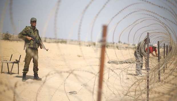 File photo shows a member of the Palestinian security forces, loyal to Hamas, standing guard as men set up a barbed wire on the border with Egypt, in Rafah in the southern Gaza Strip.
