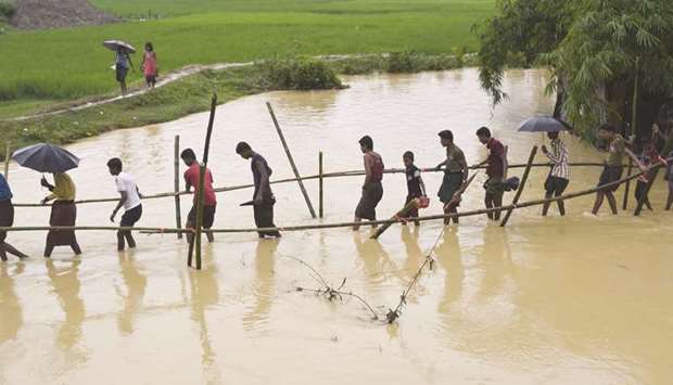 Rohingya refugees cross floodwater in Thyangkhali refugee camp near the Bangladesh town of Ukhia yesterday.