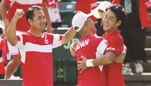 Yuoichi Sugita (right) of Japan hugs head coach Atoshi Iwabuchi after defeating Thiago Monteiro of Brazil during the Davis Cup World Group playoff in Osaka, western Japan, yesterday. (AFP)